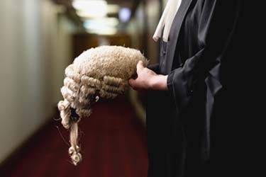 person wearing Barristers gown holding a Barristers wig